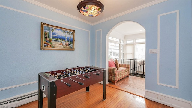 playroom with a baseboard radiator, crown molding, and hardwood / wood-style flooring