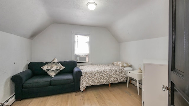 bedroom with a baseboard heating unit, a textured ceiling, cooling unit, light wood finished floors, and vaulted ceiling