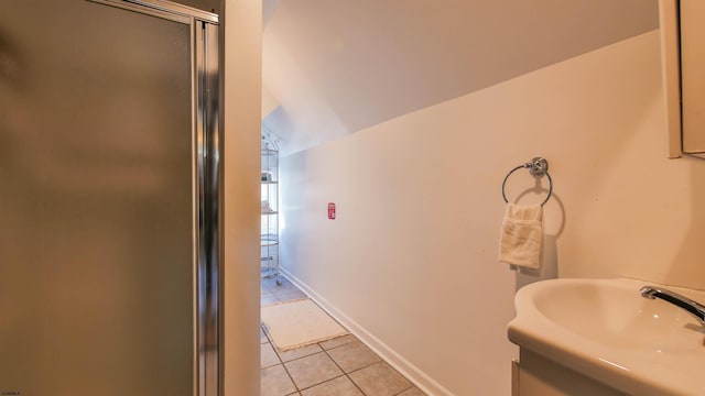 bathroom featuring lofted ceiling, a sink, a shower stall, tile patterned flooring, and baseboards