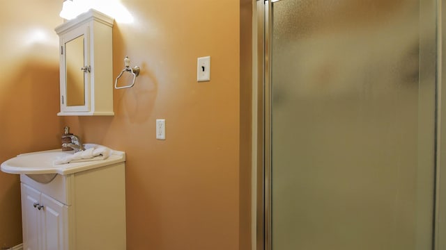 bathroom with elevator, a shower stall, and vanity