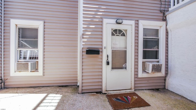 view of exterior entry with cooling unit and stucco siding