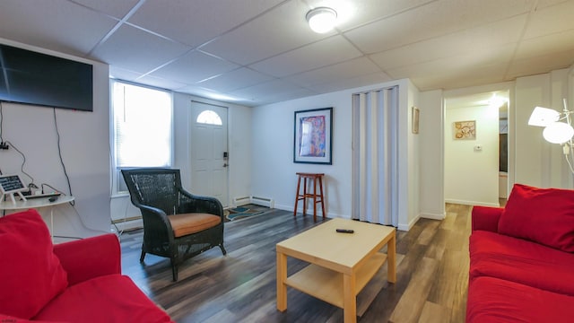 living area with a baseboard heating unit, baseboards, a drop ceiling, baseboard heating, and wood finished floors