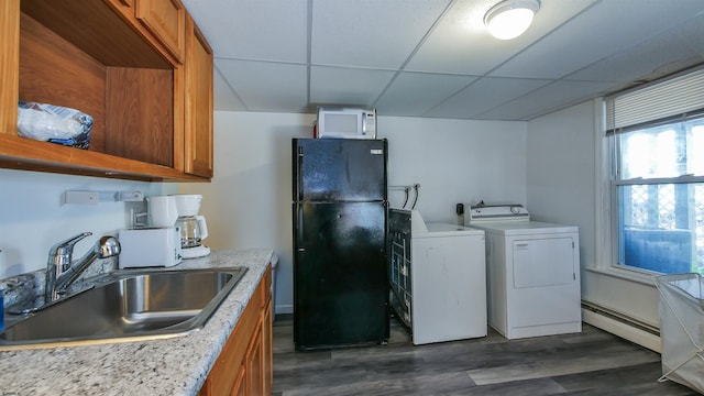 interior space featuring a drop ceiling, baseboard heating, brown cabinets, freestanding refrigerator, and a sink