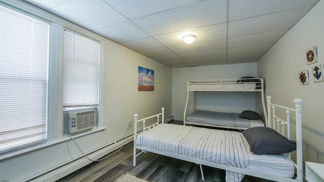 bedroom featuring cooling unit, wood finished floors, a paneled ceiling, and a baseboard radiator