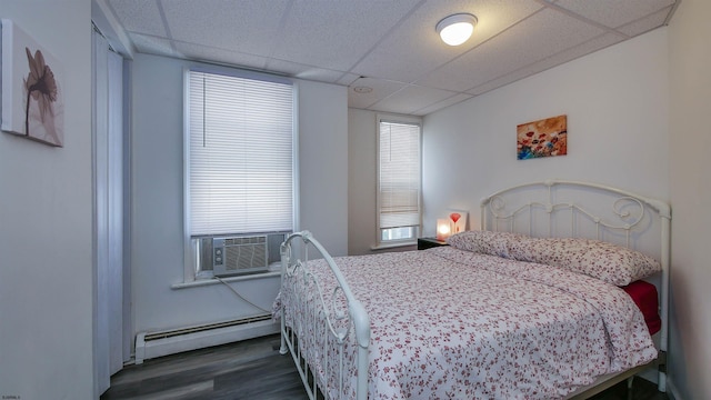 bedroom featuring dark wood-style floors, cooling unit, a paneled ceiling, and a baseboard radiator