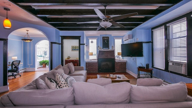 living room with an AC wall unit, wood finished floors, cooling unit, arched walkways, and a fireplace