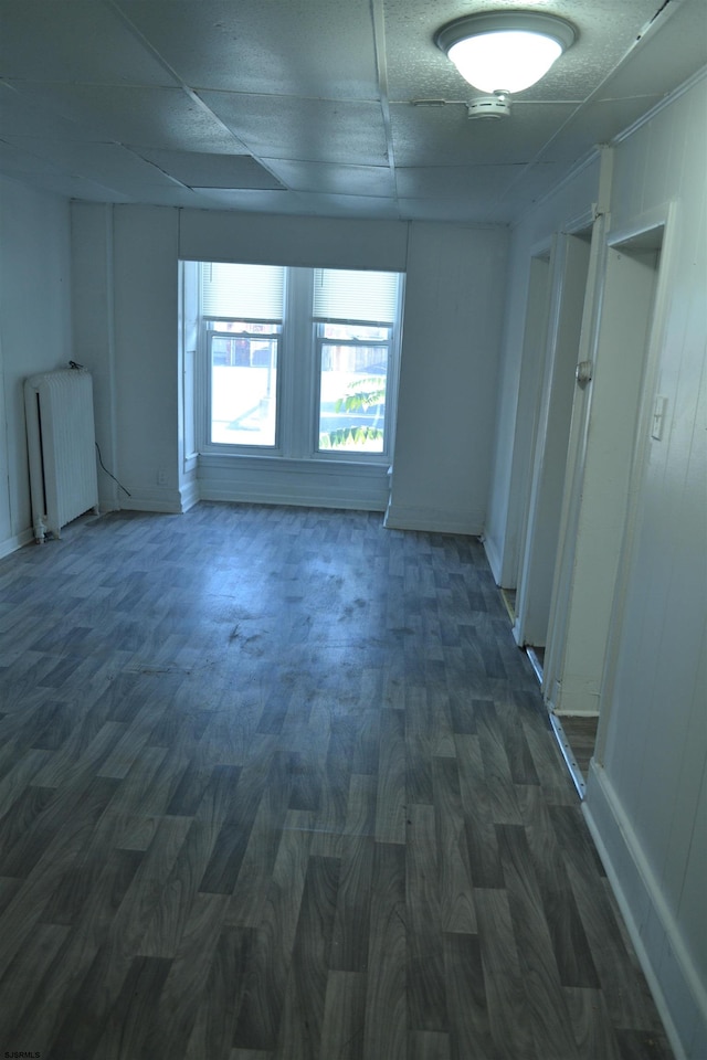 unfurnished room featuring a drop ceiling, dark hardwood / wood-style flooring, and radiator