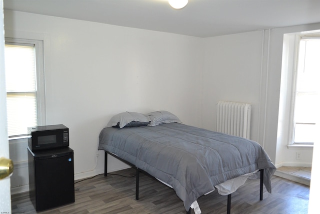 bedroom featuring radiator heating unit and hardwood / wood-style flooring