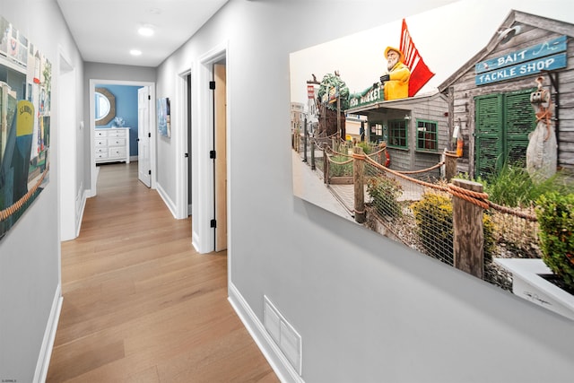 corridor featuring wood finished floors, visible vents, and baseboards