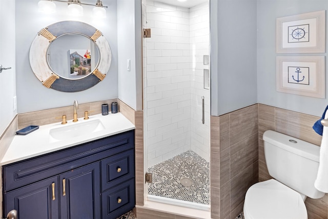 bathroom featuring a stall shower, vanity, toilet, and tile walls