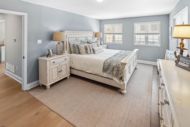 bedroom featuring visible vents, light wood-style flooring, and baseboards