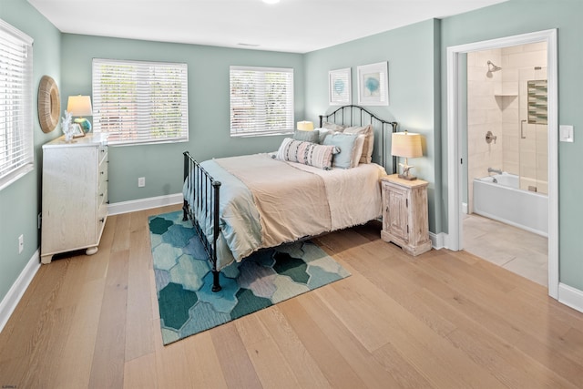 bedroom with light wood-type flooring, baseboards, and ensuite bathroom