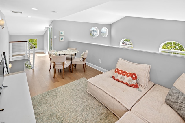 interior space featuring lofted ceiling, visible vents, a wealth of natural light, and wood finished floors