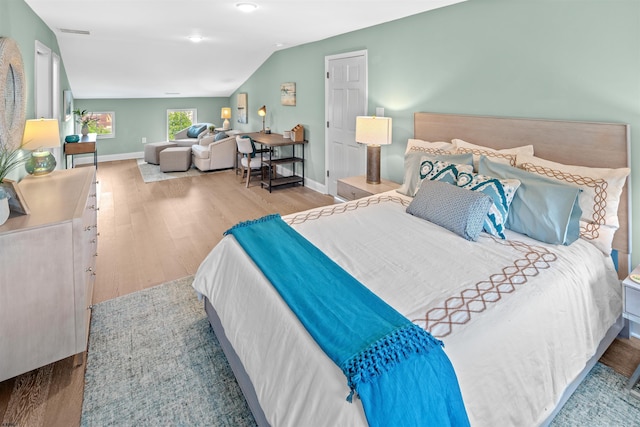 bedroom with visible vents, vaulted ceiling, baseboards, and wood finished floors