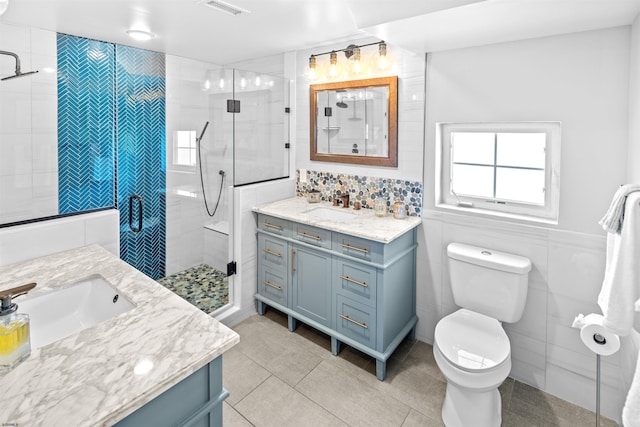 full bath featuring a stall shower, tile patterned flooring, tile walls, and vanity