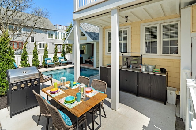 view of patio / terrace featuring a fenced in pool, outdoor dining area, fence, a balcony, and a sink