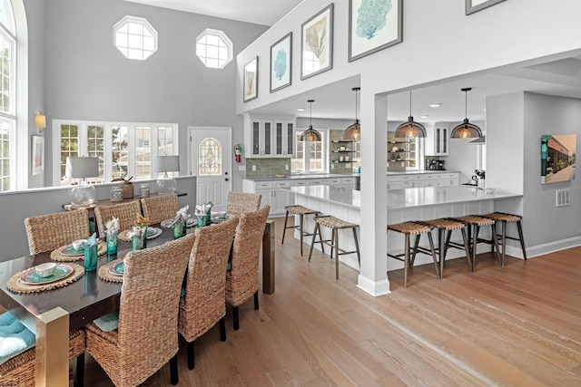 dining space with a high ceiling, light wood-style flooring, and baseboards