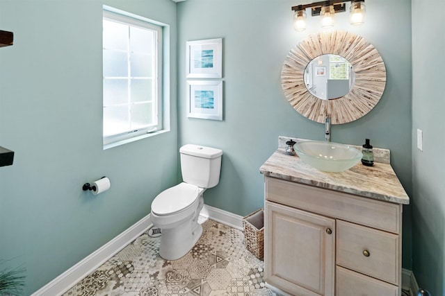 half bath with tile patterned flooring, baseboards, vanity, and toilet