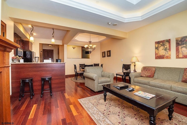 living room featuring an inviting chandelier, a raised ceiling, and dark wood-type flooring