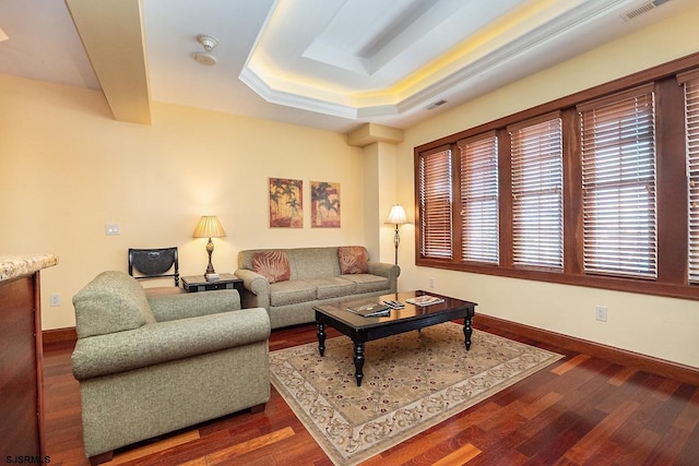 living room with dark wood-style flooring, visible vents, a raised ceiling, and baseboards