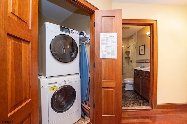 laundry area with stacked washer and dryer, laundry area, and wood finished floors