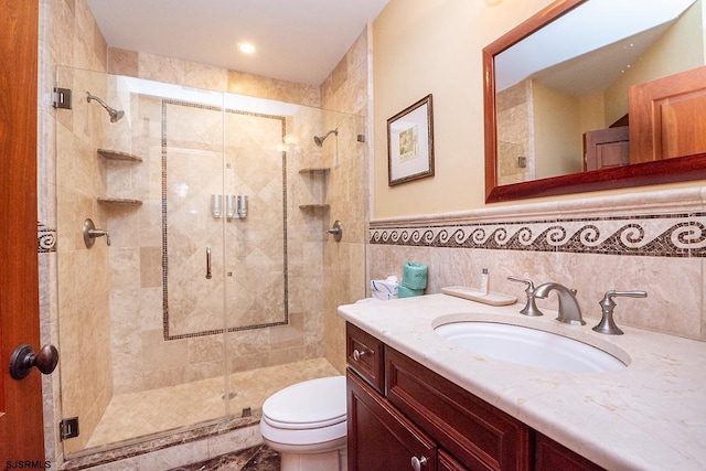 full bath featuring toilet, vanity, tile walls, wainscoting, and a shower stall