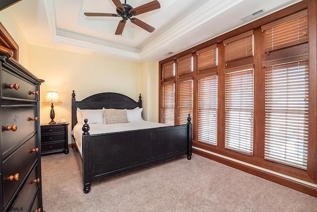 bedroom with visible vents, a raised ceiling, a ceiling fan, light colored carpet, and crown molding