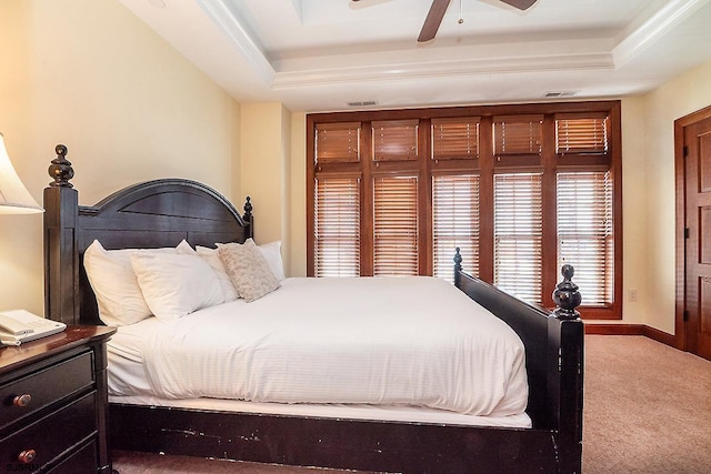 bedroom featuring a tray ceiling, carpet flooring, visible vents, and baseboards