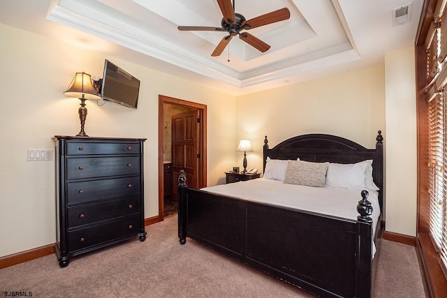 bedroom featuring light colored carpet, visible vents, baseboards, ornamental molding, and a raised ceiling