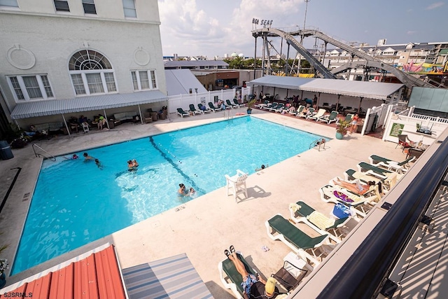 community pool with a patio and fence