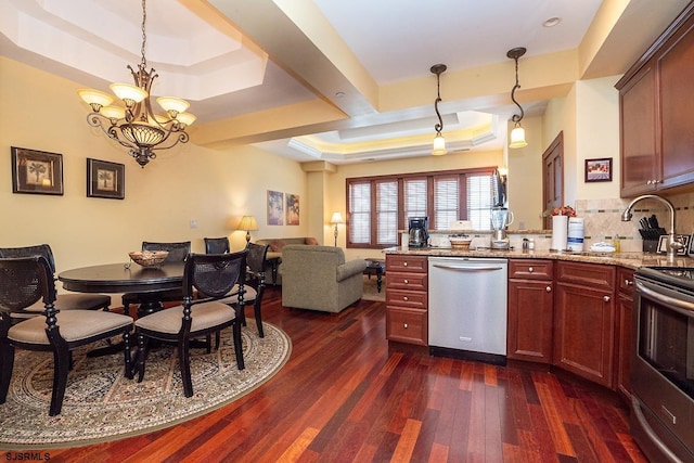 kitchen with a peninsula, open floor plan, appliances with stainless steel finishes, dark wood-style floors, and a raised ceiling