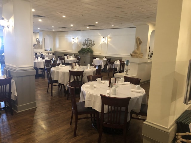 dining area with arched walkways, wood finished floors, visible vents, and a decorative wall