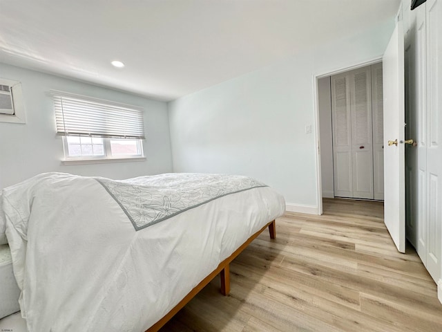 bedroom with an AC wall unit and light hardwood / wood-style floors