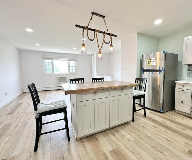 kitchen featuring white cabinetry, stainless steel fridge, pendant lighting, and light hardwood / wood-style floors