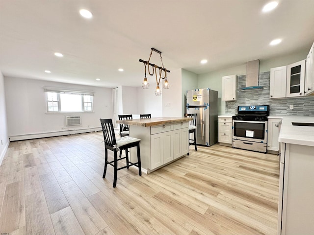 kitchen with stainless steel appliances, a baseboard radiator, wall chimney exhaust hood, and light hardwood / wood-style flooring