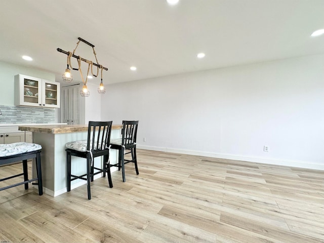 kitchen with backsplash, pendant lighting, and light hardwood / wood-style floors