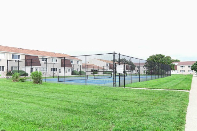 view of tennis court featuring a lawn