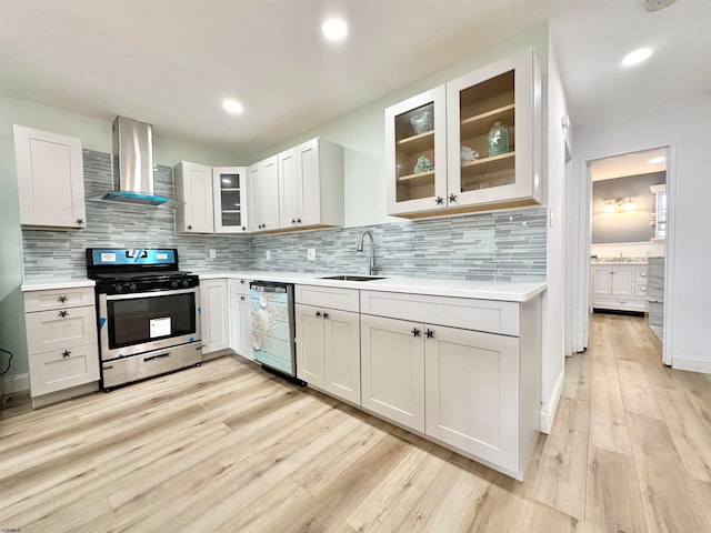 kitchen with dishwasher, light hardwood / wood-style flooring, tasteful backsplash, gas stove, and wall chimney range hood