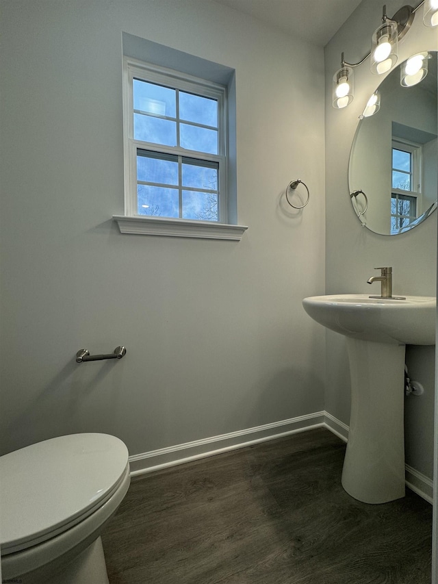 half bathroom featuring toilet, baseboards, and wood finished floors