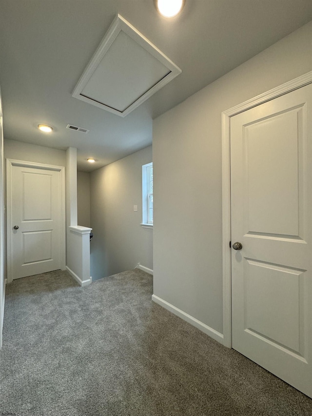 hall featuring carpet flooring, visible vents, baseboards, and an upstairs landing