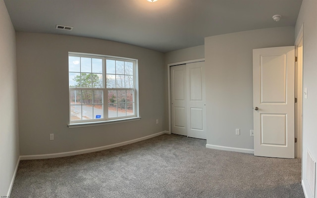 unfurnished bedroom featuring carpet floors, a closet, visible vents, and baseboards