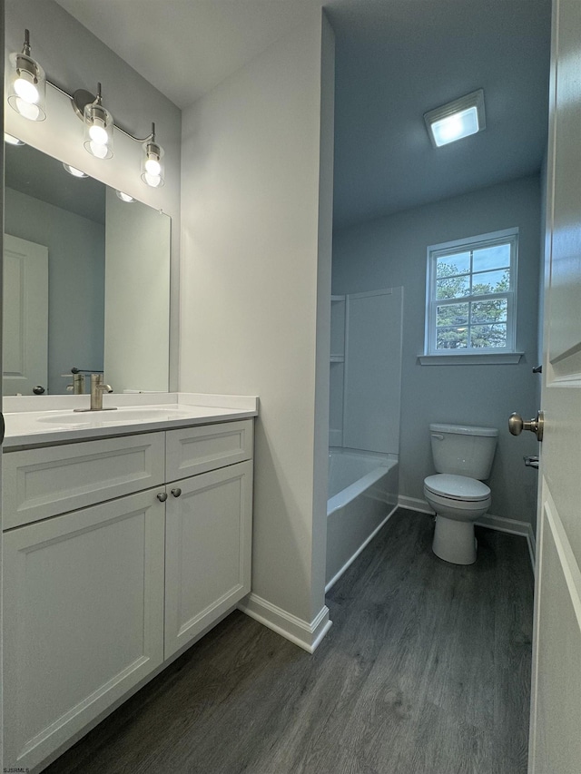 full bathroom featuring toilet, baseboards, wood finished floors, and a bath