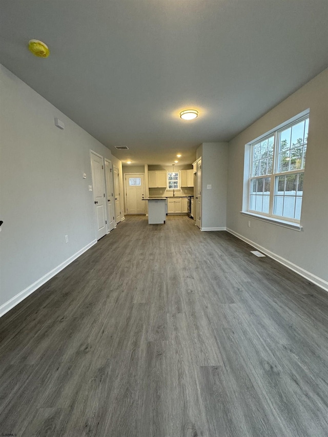 unfurnished living room featuring dark wood-style floors, visible vents, and baseboards