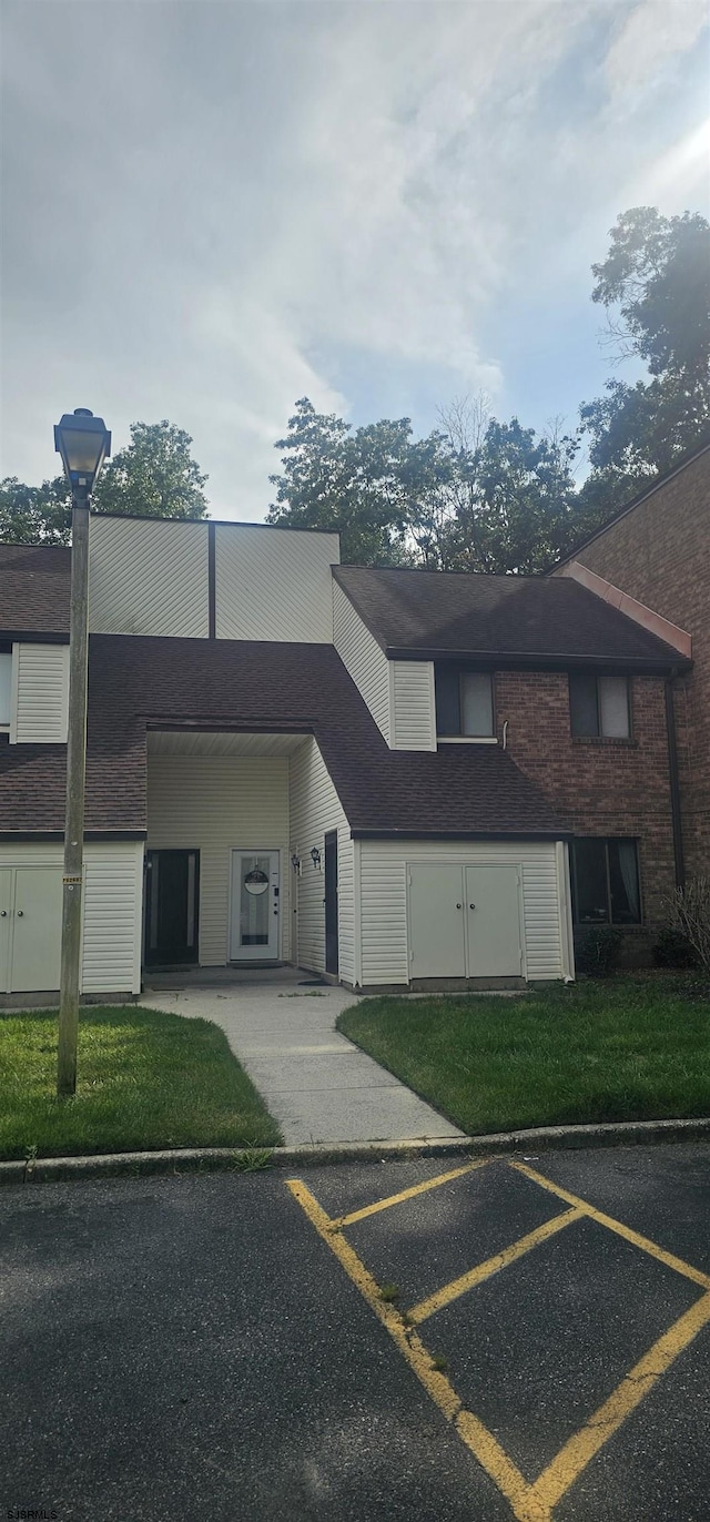 view of front facade featuring uncovered parking and a front lawn