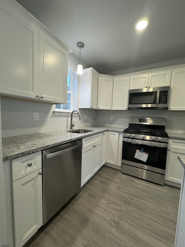 kitchen with white cabinets, sink, stainless steel appliances, and hanging light fixtures