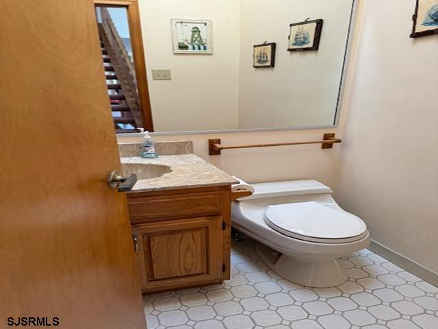 half bath featuring vanity, toilet, and baseboards