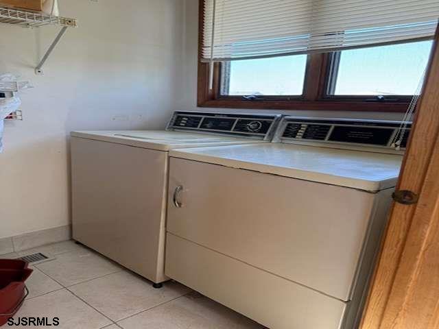 laundry room featuring light tile patterned floors, laundry area, separate washer and dryer, and baseboards