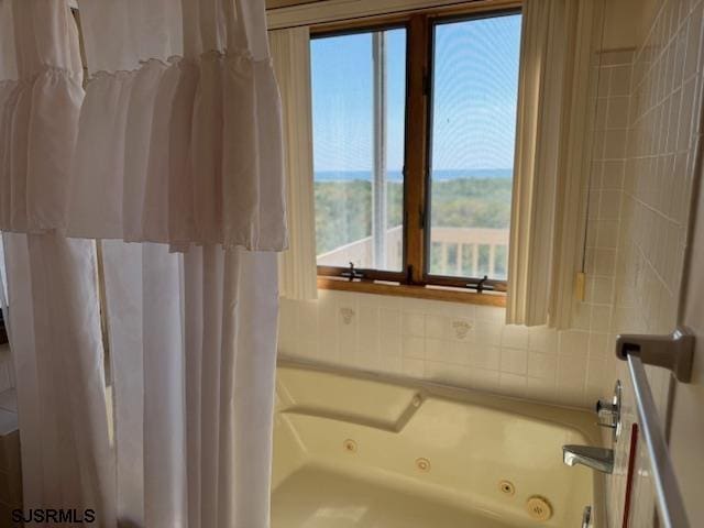 bathroom with a shower with curtain and a tub with jets