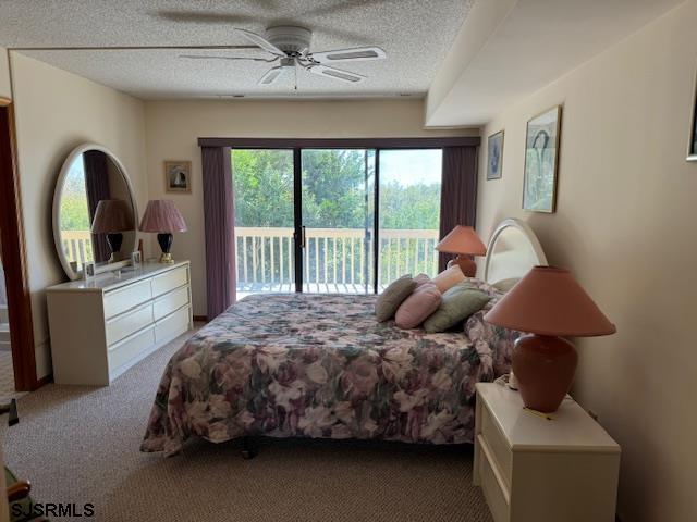 bedroom with a textured ceiling, access to outside, ceiling fan, and carpet