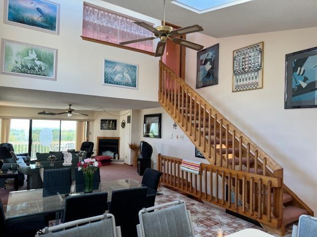 living room with high vaulted ceiling, a ceiling fan, carpet flooring, and stairs